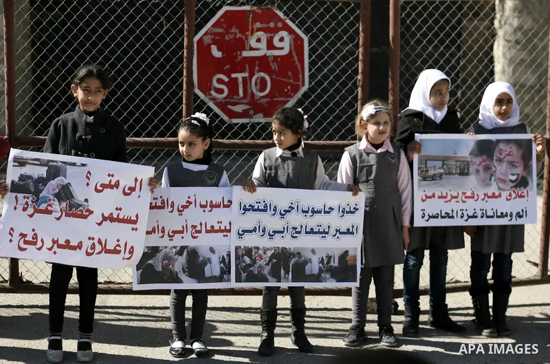 Palestinian children carry placards during a rally in front of the Rafah border crossing with Egypt in the southern Gaza Strip on January 29, 2014, demanding the permanent and unconditional opening of the crossing. Egypt...