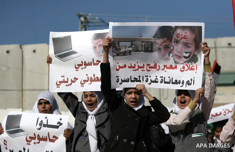 Palestinian children carry placards during a rally in front of the Rafah border crossing with Egypt in the southern Gaza Strip on January 29, 2014, demanding the permanent and unconditional opening of the crossing. Egypt...