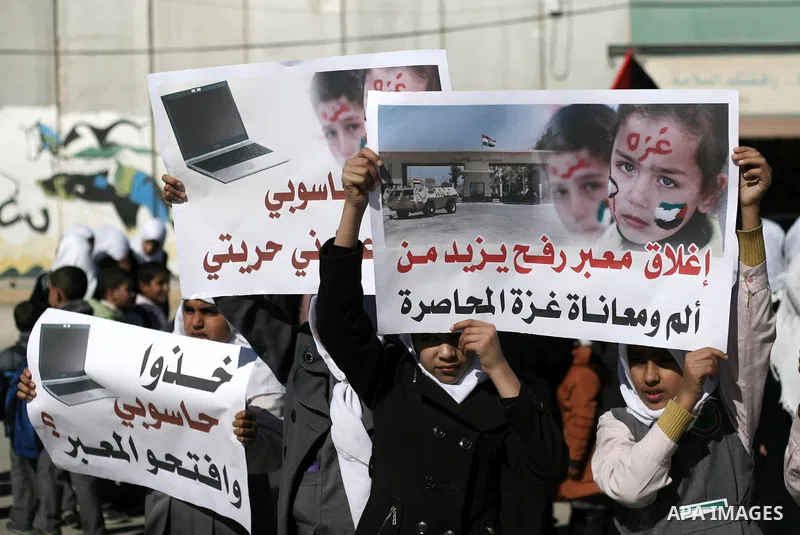 Palestinian children carry placards during a rally in front of the Rafah border crossing with Egypt in the southern Gaza Strip on January 29, 2014, demanding the permanent and unconditional opening of the crossing. Egypt...