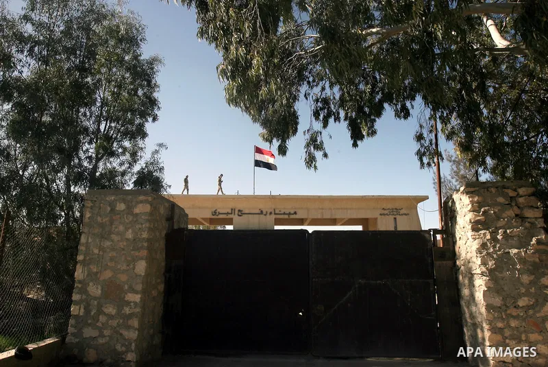 Egyptian soldiers (top) keep watch next to the national flag on the Egyptian side of the Rafah border crossing, while Palestinian children (unseen) take part in a rally on the Palestinian side calling on Egyptian authori...