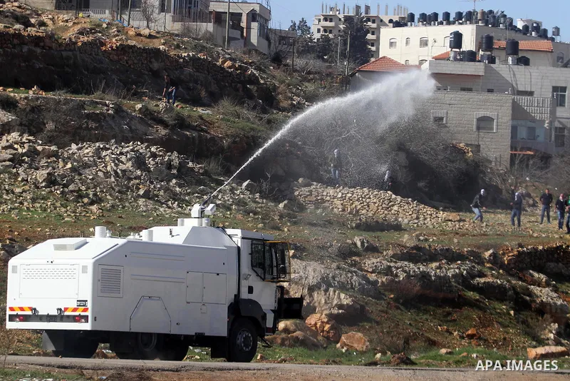 An Israeli army truck sprays foul smelling water at Palestinian students from Bir Zeit University on January 30, 2014 during clashes near the Israeli detention center of Ofer, in the occupied West Bank. The students were...