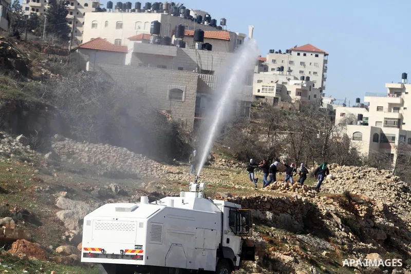 An Israeli army truck sprays foul smelling water at Palestinian students from Bir Zeit University on January 30, 2014 during clashes near the Israeli detention center of Ofer, in the occupied West Bank. The students were...