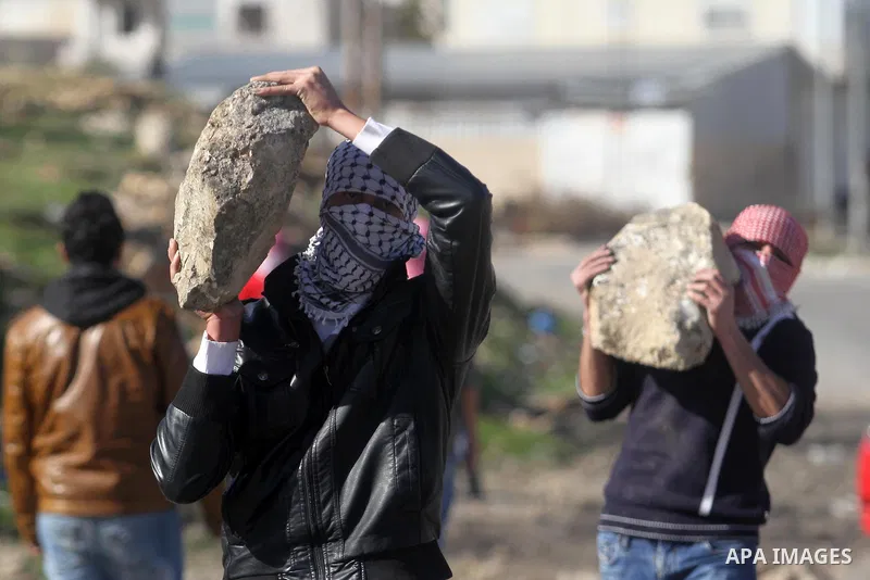 Masked Palestinian students from Bir Zeit University build a barricade during clashes against Israeli security forces on January 30, 2014 near the Israeli detention center of Offra, in the occupied West Bank. The student...