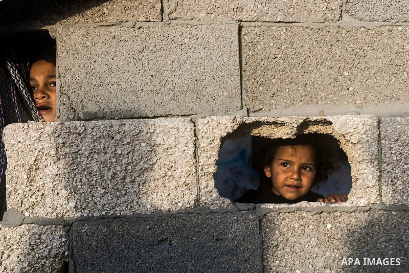 Palestinian children look through holes in a wall at their family's house at al-Shati refugee camp in the west Gaza City on January 30, 2014. Photo by Abdullah Jadallah