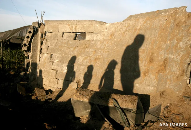 The silhouette of Palestinians is seen as they inspect a farm following an Israeli air strike that injured two Palestinians, in the southern Gaza Strip town of Rafah on January 31, 2014. Photo by Eyad Al Baba