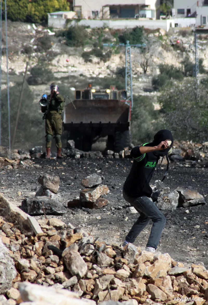 A Palestinian protester throws stones at Israeli security forces as clashes broke out during a demonstration against the expropriation of Palestinian land by Israel in the village of Kfar Qaddum, near the occupied West B...