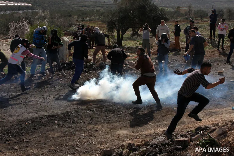 Palestinian protesters run seek for cover from tear gas fired by Israeli security forces as clashes broke out during a demonstration against the expropriation of Palestinian land by Israel in the village of Kfar Qaddum,...