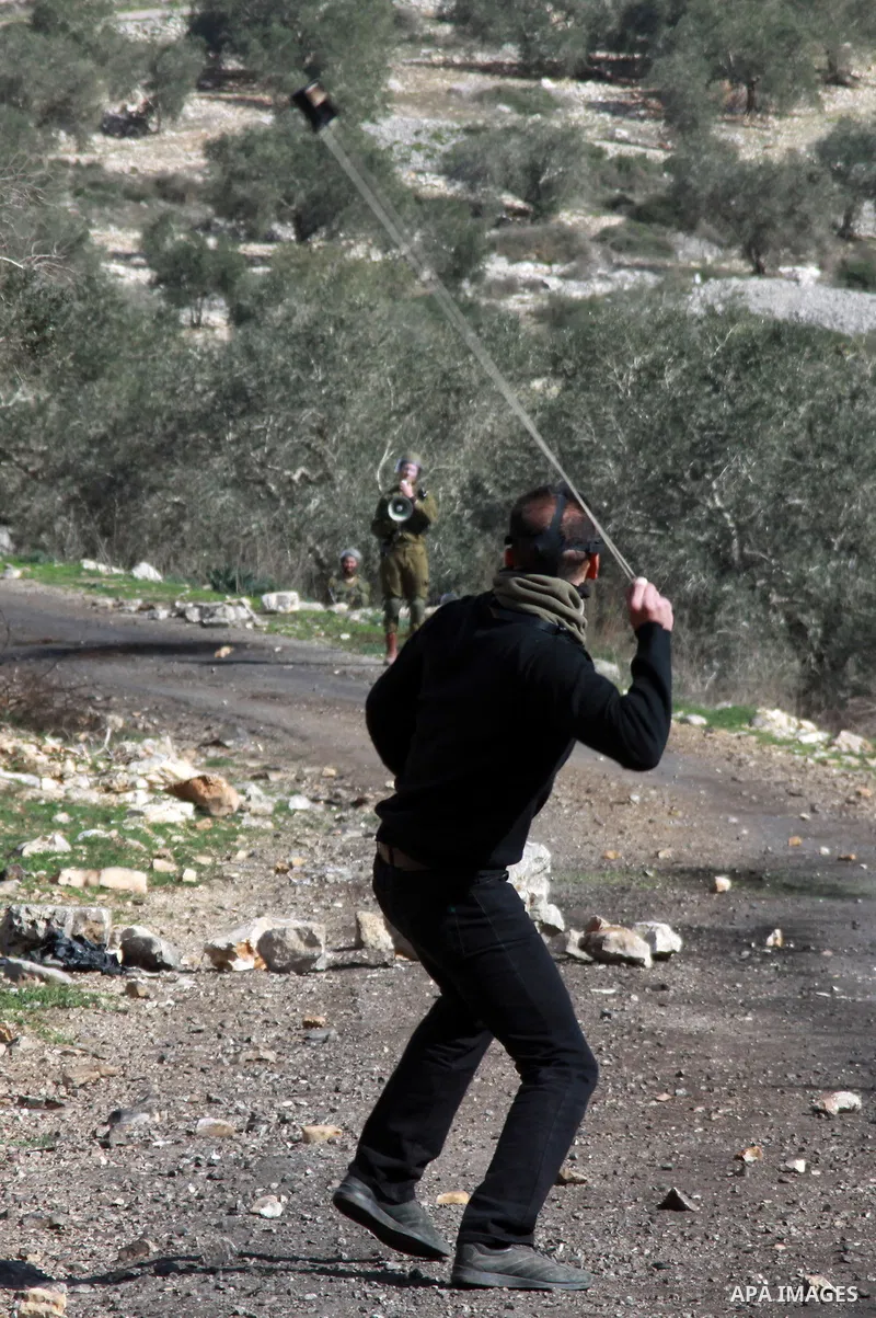 A Palestinian protester throws stones at Israeli security forces as clashes broke out during a demonstration against the expropriation of Palestinian land by Israel in the village of Kfar Qaddum, near the occupied West B...