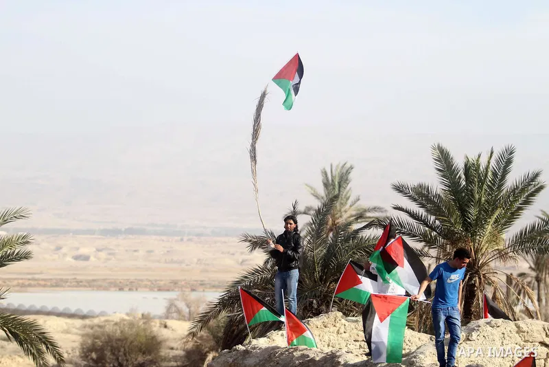 Palestinian activists hold their national flags at the site of the old village known as Ein Hijleh, in the Jordan valley near the West Bank City of Jericho, January 31, 2014. Hundreds of Palestinians announced today the...