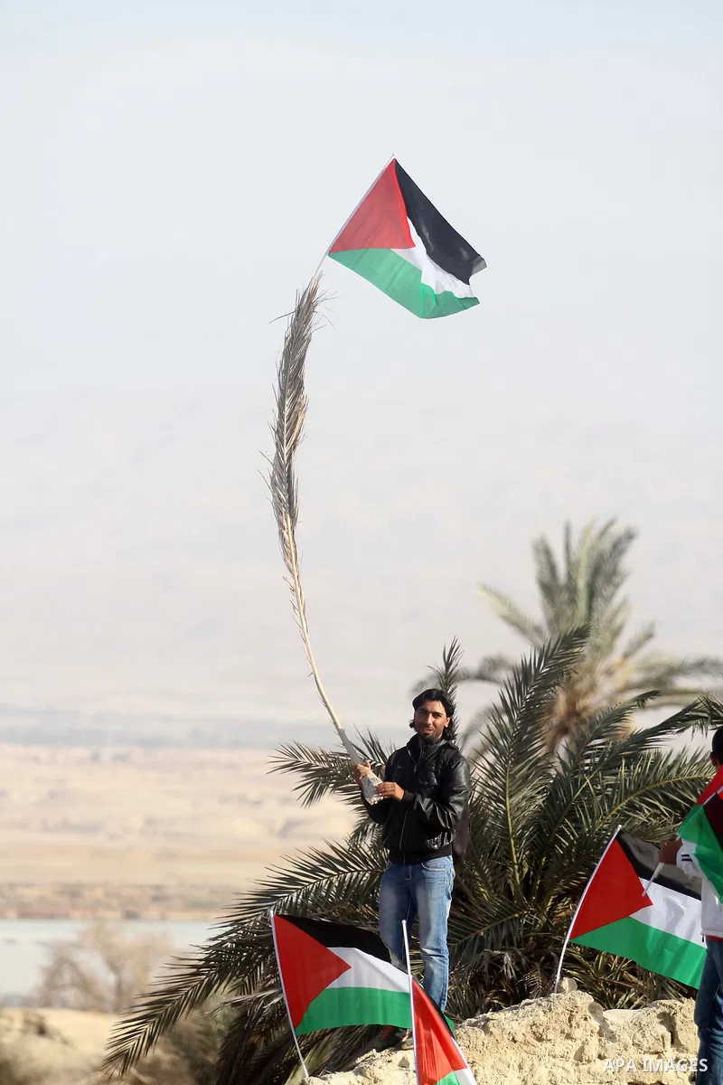 A Palestinian activist holds his national flag at the site of the old village known as Ein Hijleh, in the Jordan valley near the West Bank City of Jericho, January 31, 2014. Hundreds of Palestinians announced today the l...