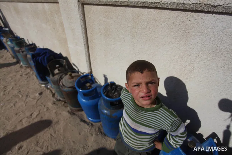 A Palestinian boy waits in line to refill cooking gas bottles at a warehouse in Deir al-Balah center Gaza Strip on Feb. 01, 2014. Photo by Ashraf Amra