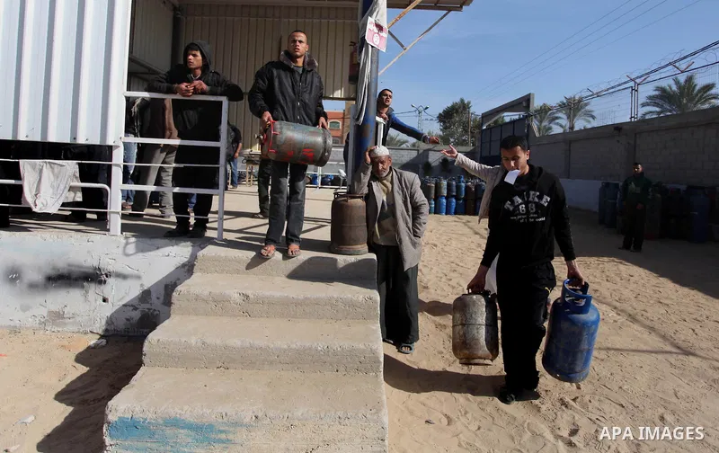 Palestinian carry a cooking gas container after refilling it at a warehouse in Deir al-Balah center Gaza Strip on Feb. 01, 2014. Photo by Ashraf Amra