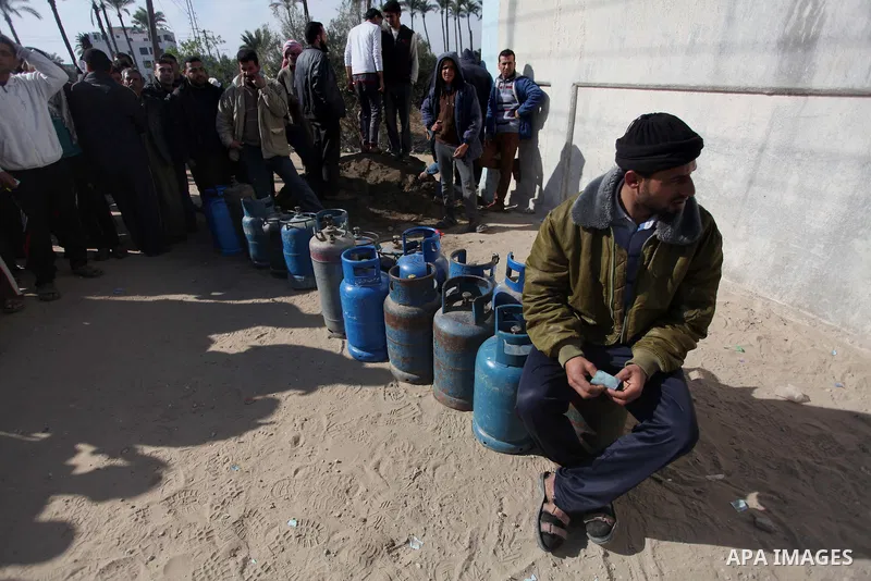 Palestinians wait in line to refill cooking gas bottles at a warehouse in Deir al-Balah center Gaza Strip on Feb. 01, 2014. Photo by Ashraf Amra