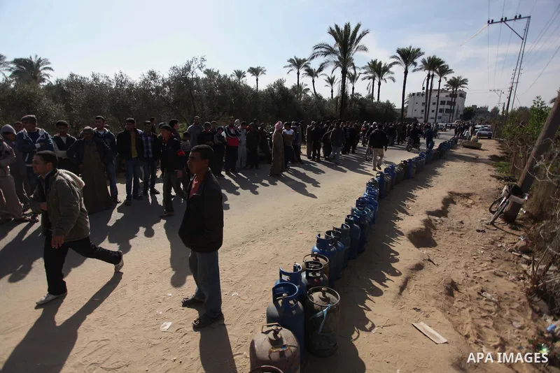 Palestinians wait in line to refill cooking gas bottles at a warehouse in Deir al-Balah center Gaza Strip on Feb. 01, 2014. Photo by Ashraf Amra