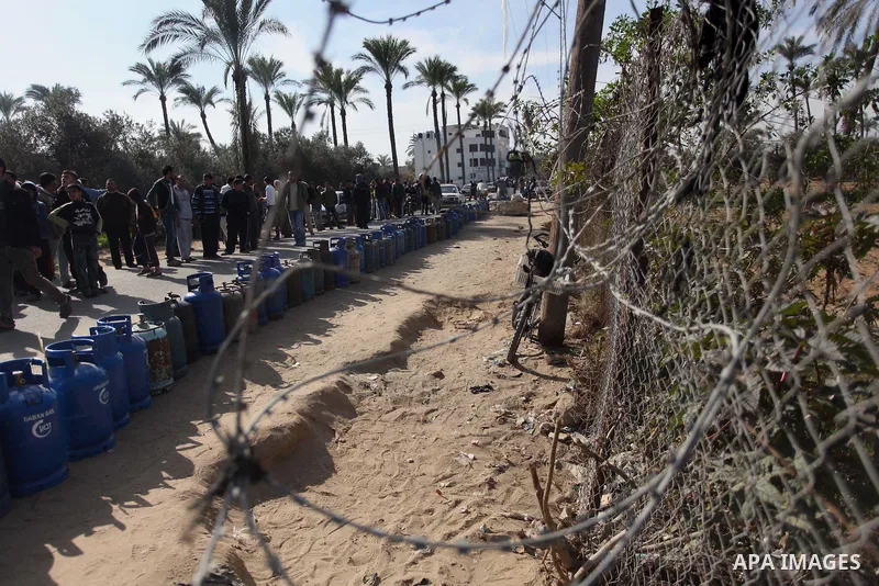 Palestinians wait in line to refill cooking gas bottles at a warehouse in Deir al-Balah center Gaza Strip on Feb. 01, 2014. Photo by Ashraf Amra