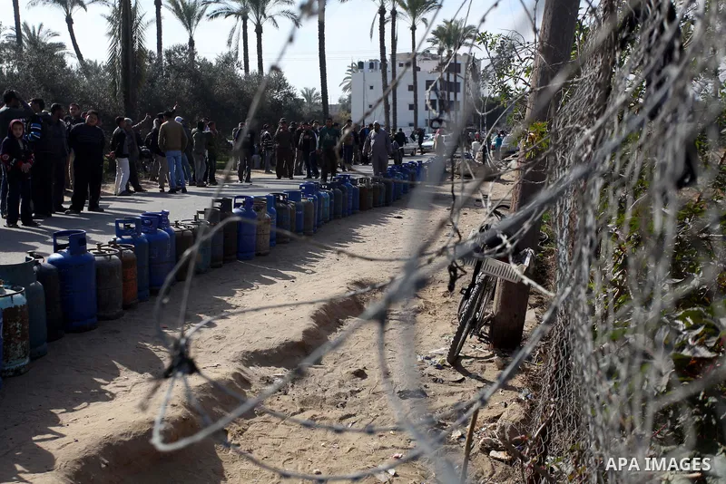 Palestinians wait in line to refill cooking gas bottles at a warehouse in Deir al-Balah center Gaza Strip on Feb. 01, 2014. Photo by Ashraf Amra