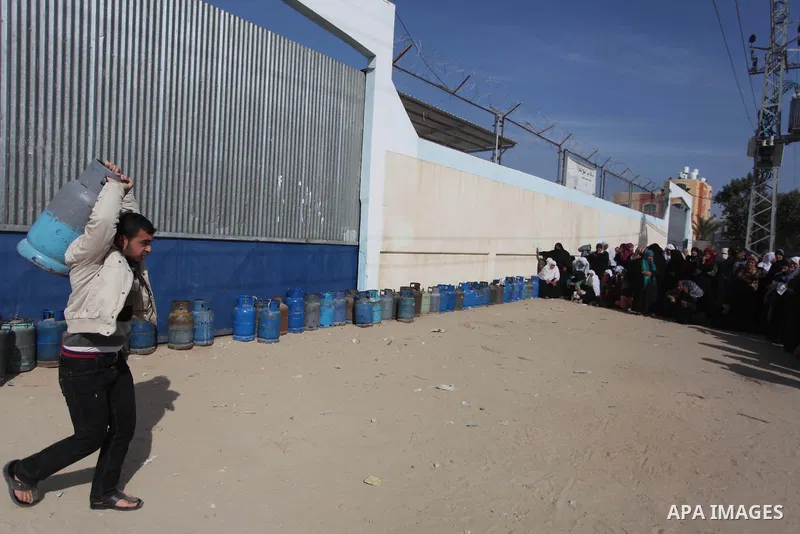 A Palestinian man carries a cooking gas container after refilling it at a warehouse in Deir al-Balah center Gaza Strip on Feb. 01, 2014. Photo by Ashraf Amra