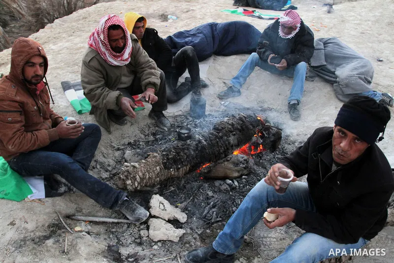 Palestinian and foreign activists warm themselves around a fire at the site of the old village known as Ein Hijleh, in the Jordan valley near the West Bank City of Jericho, Feb. 01, 2014. Hundreds of Palestinians announc...