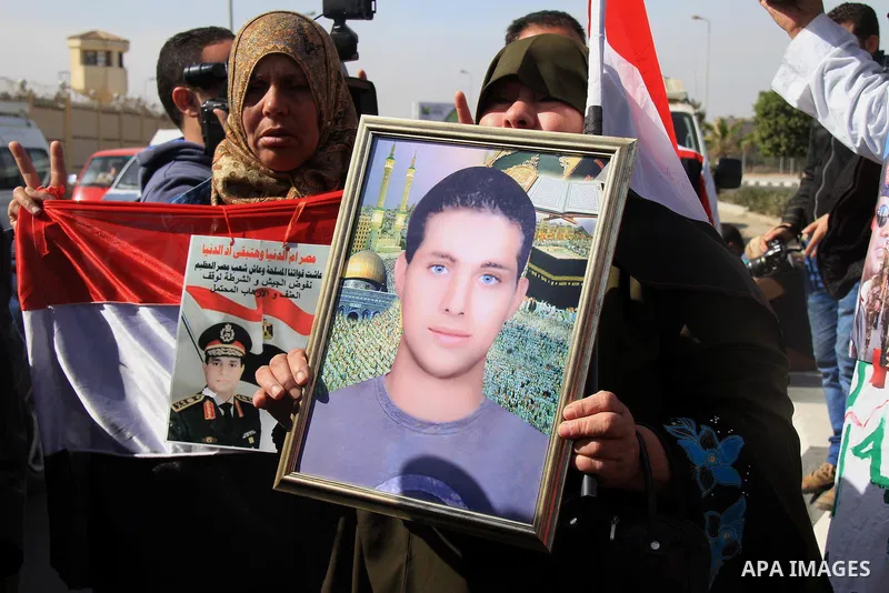 A woman carries a picture of her son who died in clashes during the presidency of Mohamed Mursi, outside a police academy where the trial of ousted Egyptian President Mursi and members of the Muslim Brotherhood is due to...