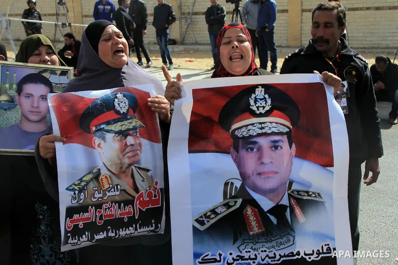 Egyptian supporters of Egypt's army chief Field Marshal Abdel Fattah al-Sisi carry a poster of Sisi in front of riot police outside a police academy, where the trial of ousted Egyptian President Mohamed Mursi and members...