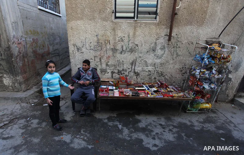 A Palestinian boy sells children stuff outside his family's house at al-Shati refugee camp, in the west Gaza City on February 02, 2014. Photo by Ashraf Amra