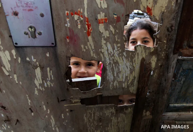 Palestinian children look through a wooden door in front their family's house at al-Shati refugee camp, in the west Gaza City on February 02, 2014. Photo by Ashraf Amra