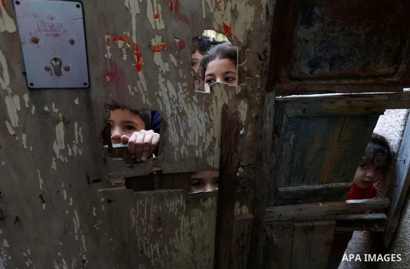 Palestinian children look through a wooden door in front their family's house at al-Shati refugee camp, in the west Gaza City on February 02, 2014. Photo by Ashraf Amra