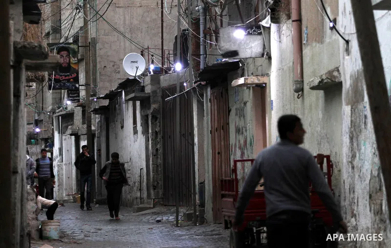 Palestinians walk at a street lighted by car batteries in Shijaiya, in Gaza City on Feb. 05, 2014. Palestinian Hassan Saad, 35 using damaged car batteries after rehabilitation for lighting dozens of homes at his neighbor...
