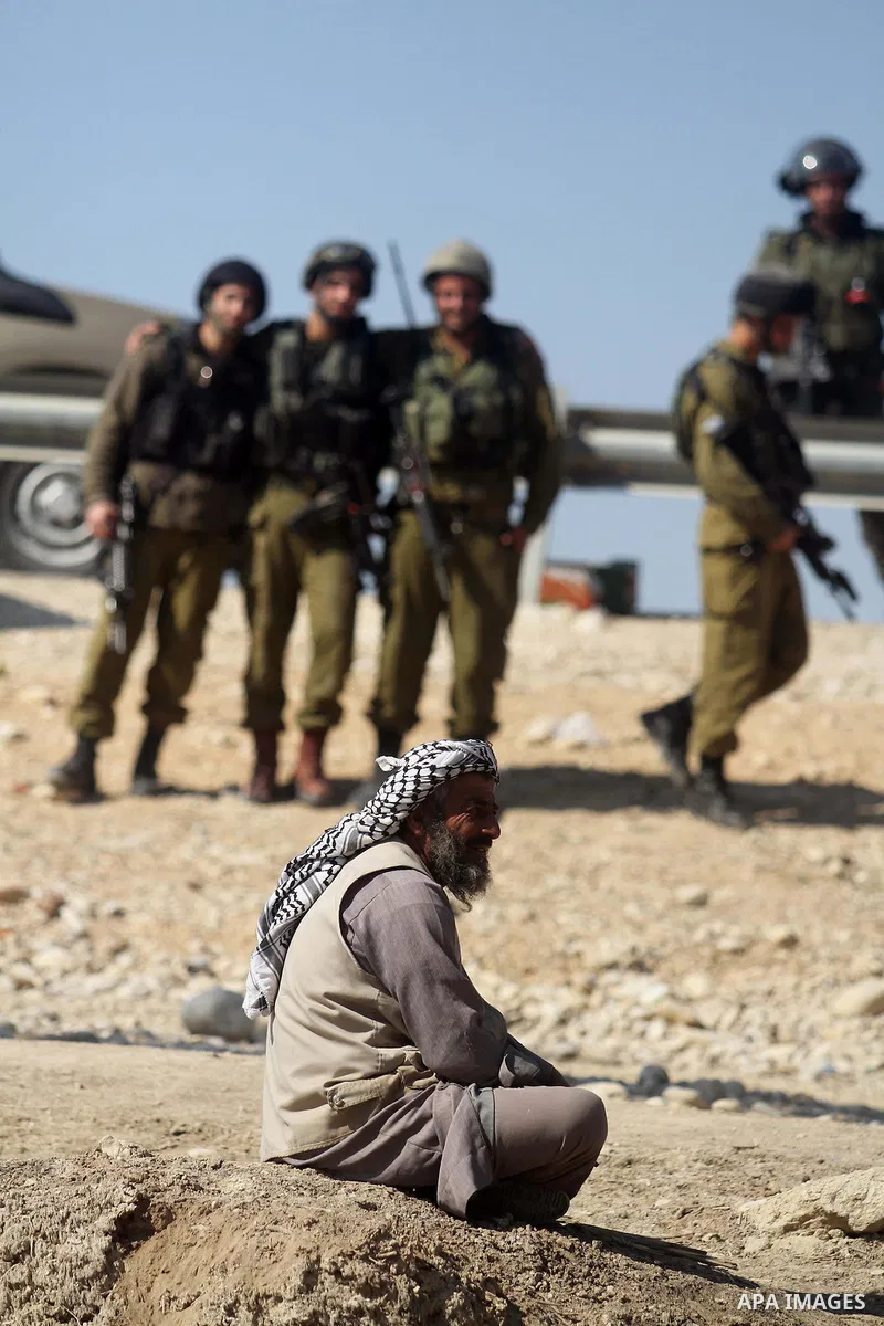 A Palestinian activist sits in front of Israeli forces during a protest in the old village of Ein Hijleh in the Jordan Valley, in a palm plantation near the West Bank city of Jericho, 05 February 2014. The protest is aim...