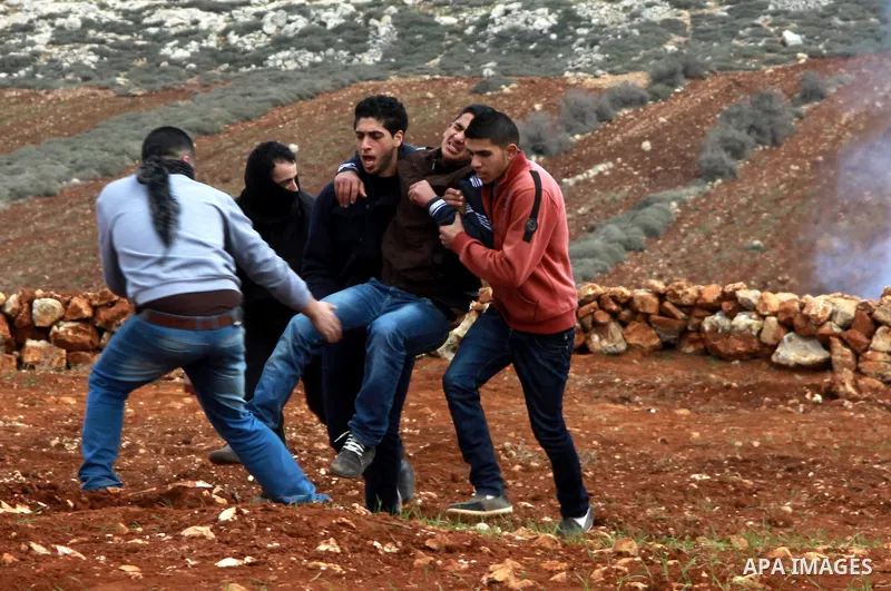 Palestinians help a wounded man during clashes with Israeli security forces following a confrontation between Palestinians and Jewish settlers, in the West Bank village of Qusra, near Nablus, Feb. 6, 2014. Clashes broke...