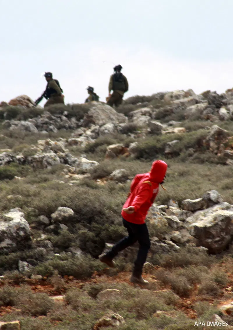 A Palestinian youth throws stones at Israeli security forces during clashes following a confrontation between Palestinians and Jewish settlers, in the West Bank village of Qusra, near Nablus, Feb. 6, 2014. Clashes broke...