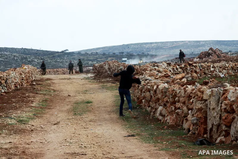 A Palestinian youth throws stones at Israeli security forces during clashes following a confrontation between Palestinians and Jewish settlers, in the West Bank village of Qusra, near Nablus, Feb. 6, 2014. Clashes broke...