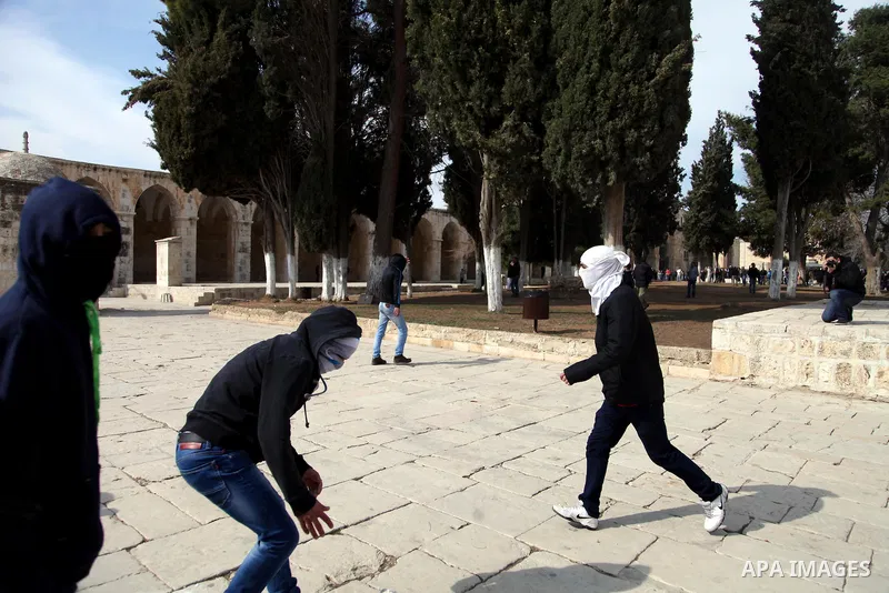 Palestinians throws a stone during clashes with Israeli police after Friday prayers on the compound known to Muslims as Noble Sanctuary and to Jews as Temple Mount in Jerusalem's Old City February 7, 2014. Israeli police...