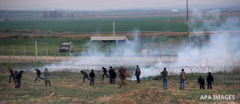 Palestinians run for cover from tear gas during clashes with Israeli forces near the border with Israel, east of Jabalia refugee camp in northern Gaza Strip on February 7, 2014. The Israeli army fired live rounds and tea...