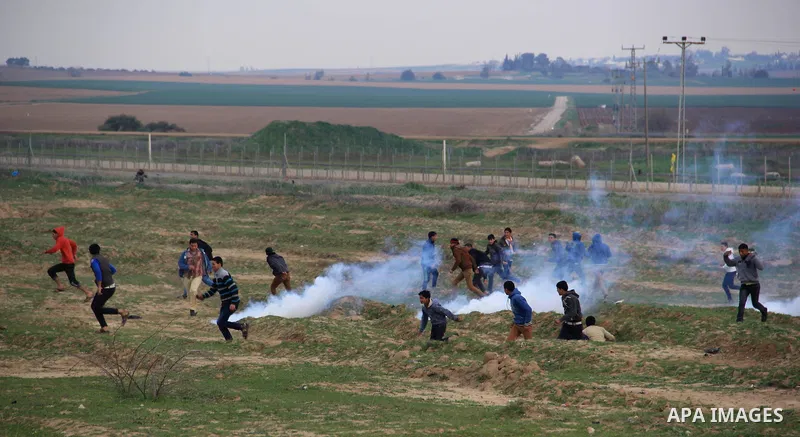 Palestinians run for cover from tear gas during clashes with Israeli forces near the border with Israel, east of Jabalia refugee camp in northern Gaza Strip on February 7, 2014. The Israeli army fired live rounds and tea...