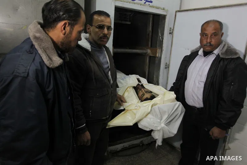 Palestinian medics and relatives look at the lifeless body of Ibrahim al-Saidi, 25, at the morgue of Al-Aqsa hospital in Deir Al Balah, central Gaza Strip, Feb. 07, 2014. A Palestinian was killed and two others were inju...