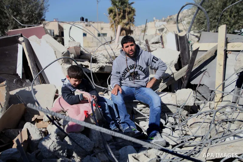 Palestinian man sits with his son on the rubble of his house after it was demolished by Israeli municipality diggers that the authorities believe without municipal permission in the neighborhood of 'Wade advent' of the t...