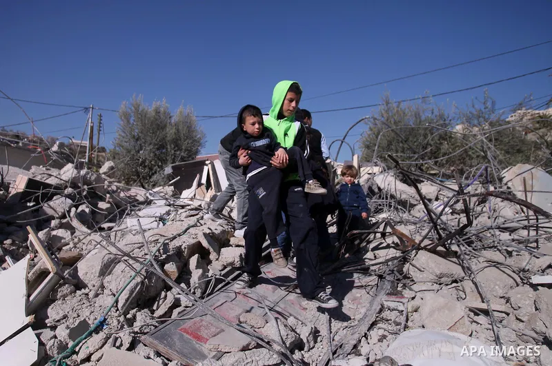 A Palestinian man stands with his children on the rubble of his house after it was demolished by Israeli municipality diggers that the authorities believe without municipal permission in the neighborhood of 'Wade advent'...