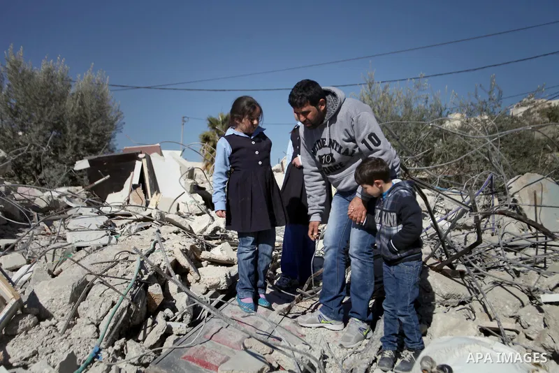 A Palestinian man stands with his children on the rubble of his house after it was demolished by Israeli municipality diggers that the authorities believe without municipal permission in the neighborhood of 'Wade advent'...