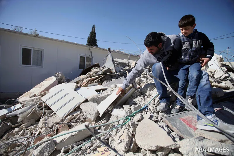 Palestinian man sits with his son on the rubble of his house after it was demolished by Israeli municipality diggers that the authorities believe without municipal permission in the neighborhood of 'Wade advent' of the t...