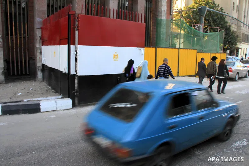 Egyptians walk past a gate at Al-Qasr Al-Aini street in downtown Cairo, February 10, 2014. A concrete wall blocking Qasr Al-Aini street which set to prevent protesters or rioters entering streets leading to the nearby in...