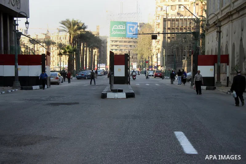 Egyptians walk past a gate at Al-Qasr Al-Aini street in downtown Cairo, February 10, 2014. A concrete wall blocking Qasr Al-Aini street which set to prevent protesters or rioters entering streets leading to the nearby in...
