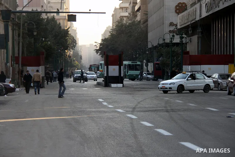 Egyptians walk past a gate at Al-Qasr Al-Aini street in downtown Cairo, February 10, 2014. A concrete wall blocking Qasr Al-Aini street which set to prevent protesters or rioters entering streets leading to the nearby in...