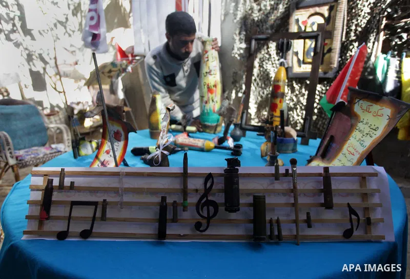 Palestinian Mohammed al-Zomar, 32, displays the remains of Israeli ammunition on wooden music notations that he designed, at his studio in the central Gaza Strip February 12, 2014. Al-Zomar draws and paints on remains of...