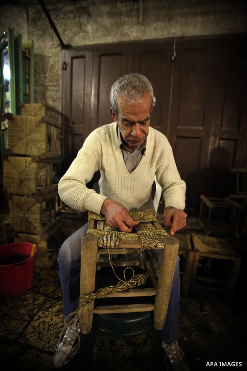 A Palestinian man works on traditional chairs made from straw in front of his workshop in Jerusalem's Old City on February 12, 2014. Minister of Holy Places for the PA Mahmoud al-Habbash told Israel's Channel 10 network...