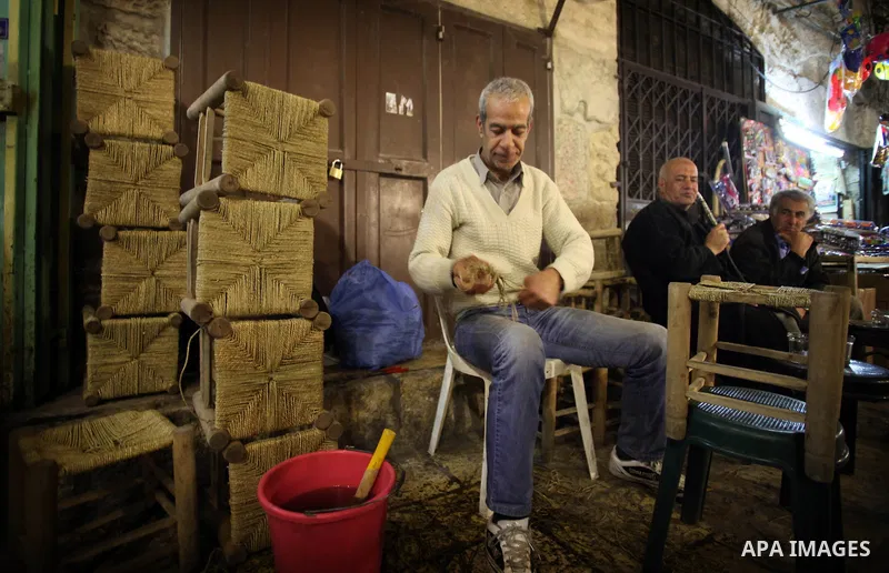 A Palestinian man works on traditional chairs made from straw in front of his workshop in Jerusalem's Old City on February 12, 2014. Minister of Holy Places for the PA Mahmoud al-Habbash told Israel's Channel 10 network...