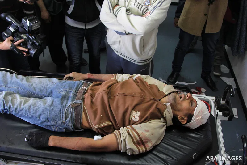 Palestinian relatives stand next to the body of Ibrahim Suleiman Mansour, 26, dead by Israeli security forces at a hospital in Gaza City on February 13, 2014. A Palestinian man was moderately injured Thursday and another...