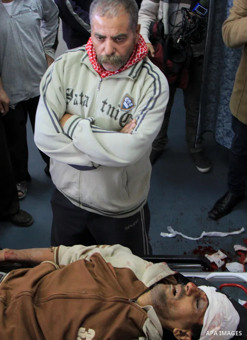 Palestinian relatives stand next to the body of Ibrahim Suleiman Mansour, 26, dead by Israeli security forces at a hospital in Gaza City on February 13, 2014. A Palestinian man was moderately injured Thursday and another...