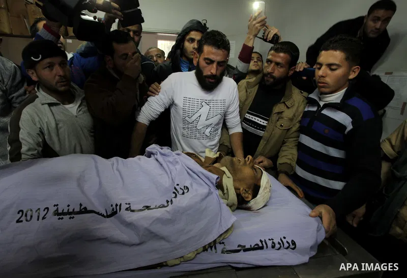 Palestinian relatives stand next to the body of Ibrahim Suleiman Mansour, 26, dead by Israeli security forces at a hospital in Gaza City on February 13, 2014. A Palestinian man was moderately injured Thursday and another...