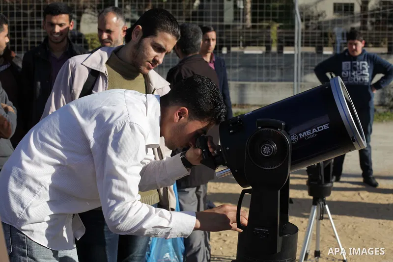 A Palestinian student looks through a telescope at the sun during a practical astronomer training to identify the Sunspot color and its impact, in Gaza City on February 13, 2014. Photo by Ashraf Amra